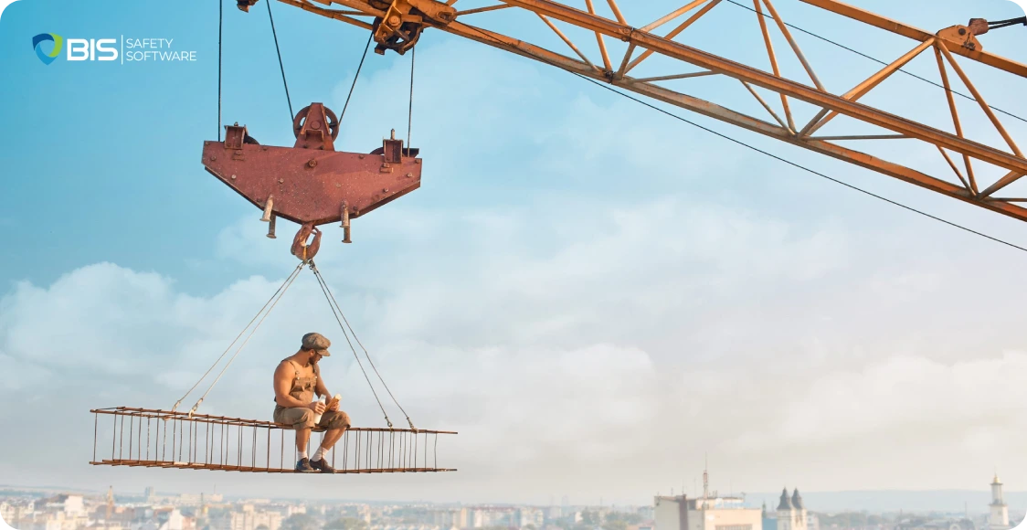 Construction worker dangerously suspended on a crane platform without safety gear.