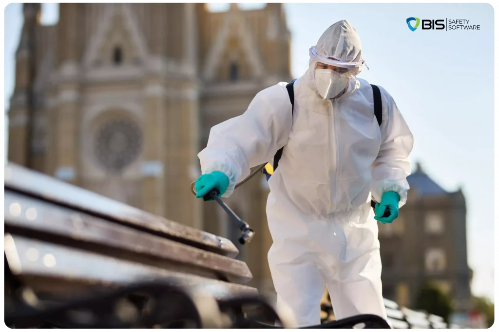 A man wearing a hazmat suit, disinfecting public benches.