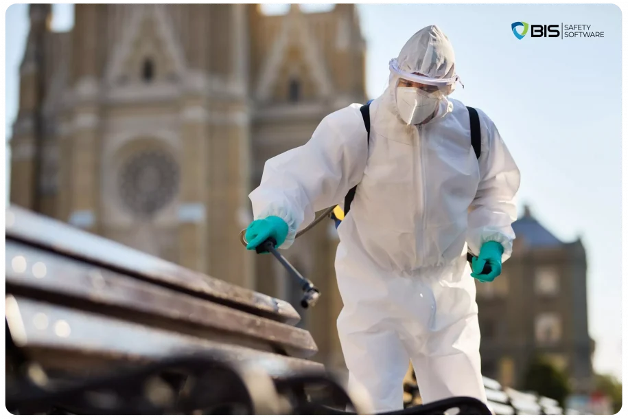 A man wearing a hazmat suit, disinfecting public benches.