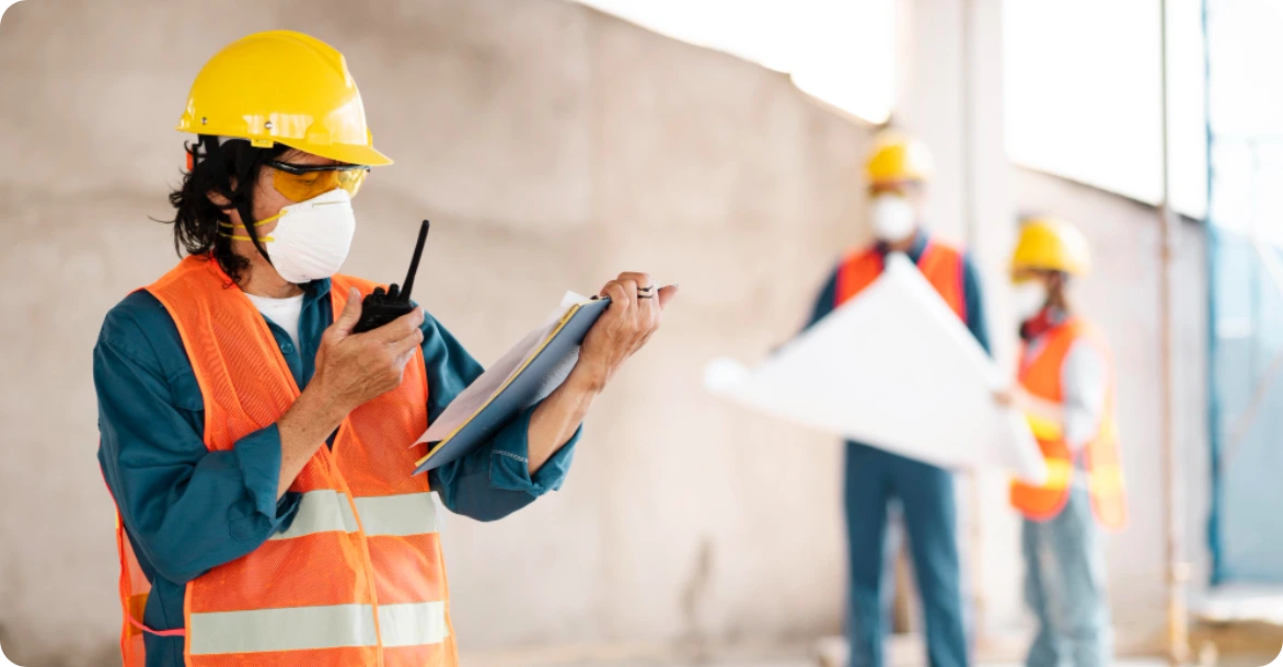 Jobsite supervisor tracks training progress while workers review blueprints, highlighting integrated and hands-on learning.