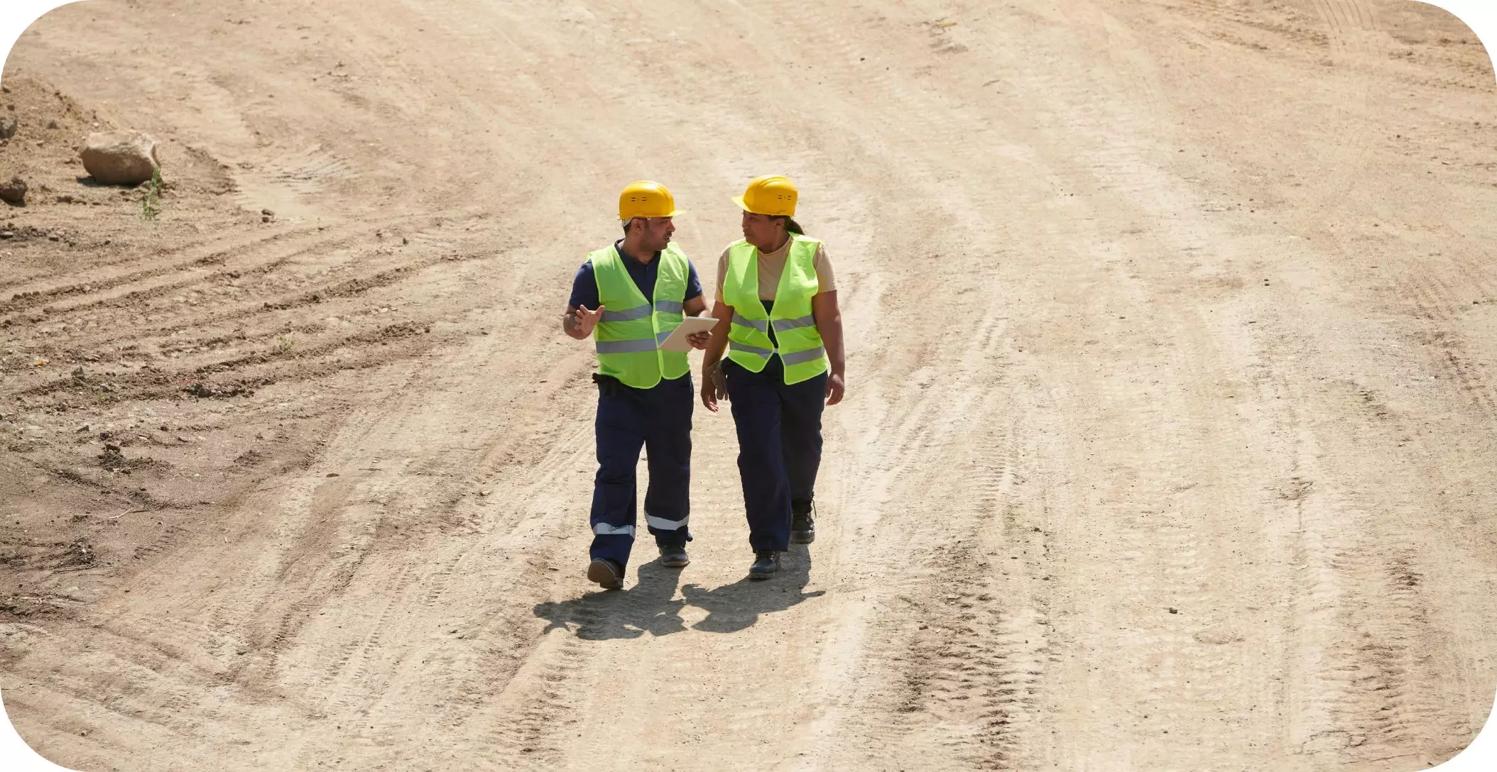 Workers in PPE having a conversation at a construction site.