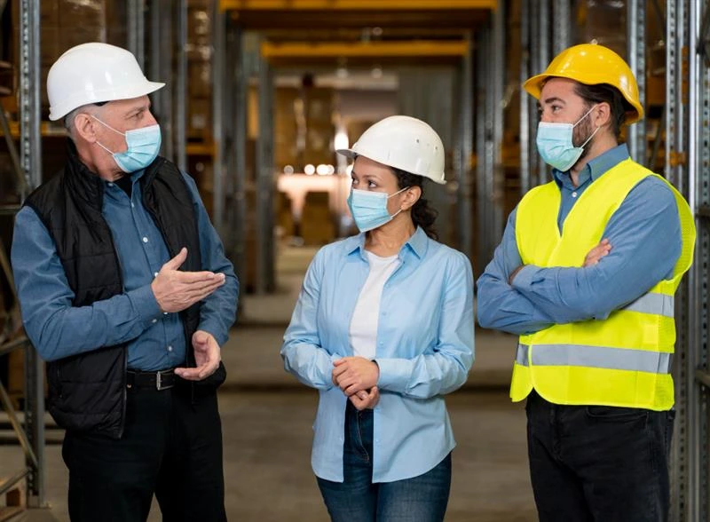 Supervisors and staff holding a safety conversation in a warehouse, underscoring how trust and communication prevent silent hazards.